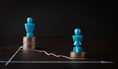 Male and female chess pieces sitting on top of coins... the female coin pile is smaller than the male