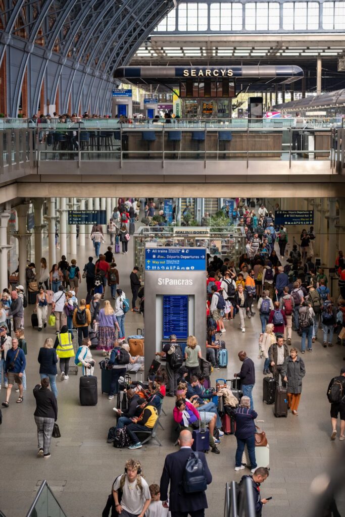A busy station concourse at St Pancras Station with people walking through and sitting waiting on trains